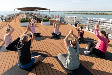 gesund-und-fit-mit-dorrit-auf-dem-rhein-2.jpg Gruppe macht Yoga auf dem Deck eines Schiffes.
