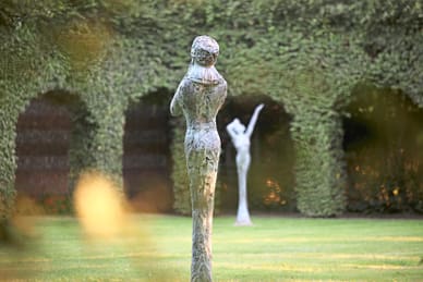 gartenparadiese-an-der-seine-3.jpg Zwei Skulpturen im Garten vor einer Efeuwand.