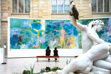 die-seine-und-ihre-impressionisten-5.jpg Zwei Personen betrachten ein grosses farbenfrohes Gemälde neben einer weissen Statue im Museum.