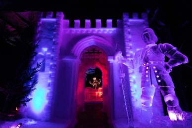 winter-magie-aus-licht-und-eis-1.jpg Beleuchtete Eisskulptur eines Ritters vor einem Eistorbogen.