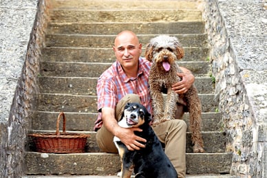 burgunder-trueffel-bei-olivier-devevre-auf-der-farm-fruigoug.jpg Mann mit zwei Hunden auf einer Steintreppe.