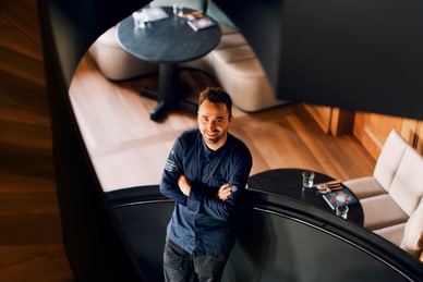 Mann steht in Wendeltreppe, lächelt nach oben.