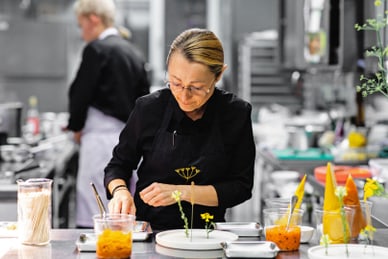 Koch in schwarzer Schürze, der in einer Restaurantküche arbeitet.