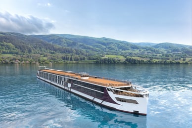 Flusskreuzfahrtschiff auf einem ruhigen Fluss vor bewaldeten Hügeln.