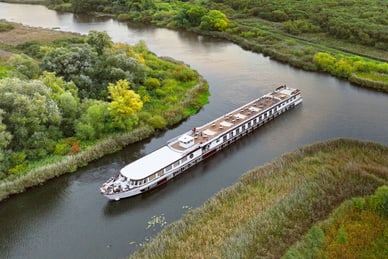 Das Flussschiff Excellence Coral gleitet auf der Peene bei Demmin durch üppige Flusslandschaft, aufgenommen aus der Luft.