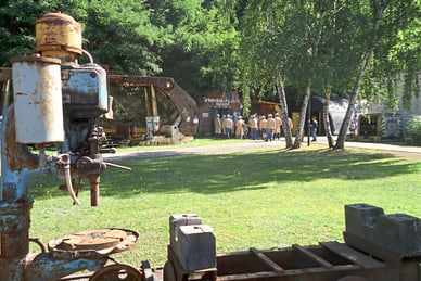 erlebnisbergwerk-velsen.jpg Altes Bergbaugerät im Freien mit Gruppenbesuch im Hintergrund.