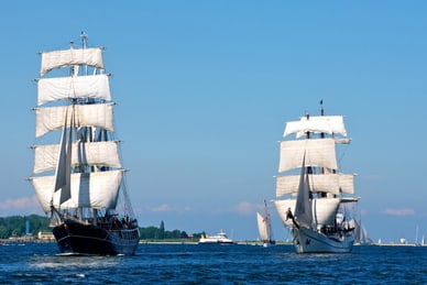 windjammerfahrt-an-der-kieler-woche-abreise-19-06.jpg Zwei Segelschiffe auf dem Meer bei klarem Himmel.