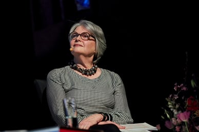 grand-tour-berlin-basel-1.jpg Ältere Frau mit Brille und Mikrofon sitzt und schaut nach oben.
