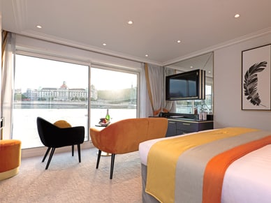Geräumige Suite auf der Excellence Crown mit Doppelbett, Sitzecke und Panoramafenster mit Flussblick.