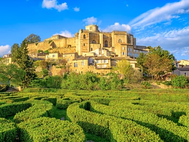 Geometrisch angelegter Heckengarten in Grignan mit historischer Altstadt auf dem Hügel dahinter.