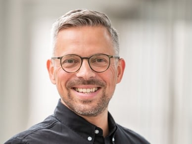 Sascha Mahl, Stadtführer in Frankfurt, lächelt mit grauem Haar und runder Brille in die Kamera.