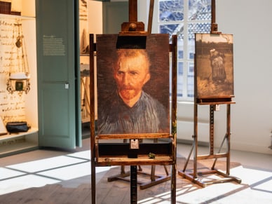 Ein Kunststudio mit Staffeleien und Gemälden in einem hellen Raum.