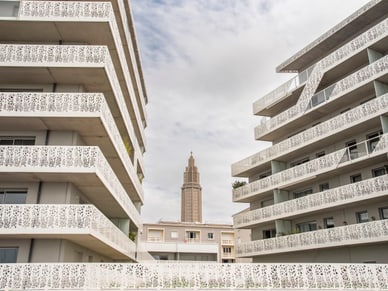 Zwei modernistische Gebäude mit perforierten Fassaden flankieren den schlanken Turm der Église Saint-Joseph in Le Havre.