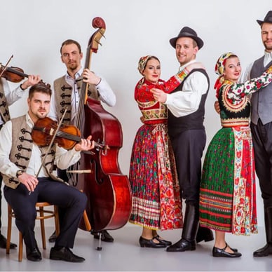 Gruppe in traditioneller Tracht mit Musikinstrumenten und Tanz.