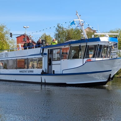 Weisse Fähre fährt auf einem Fluss unter blauem Himmel.