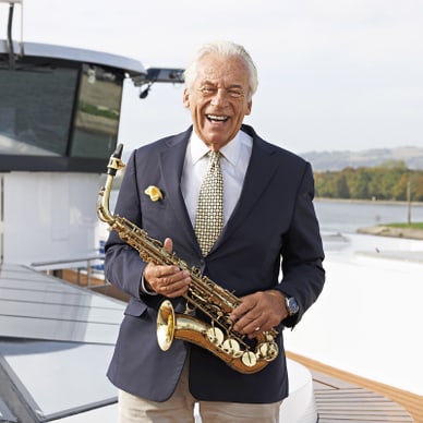 Älterer Mann in Anzug mit Saxophon auf einem Boot.