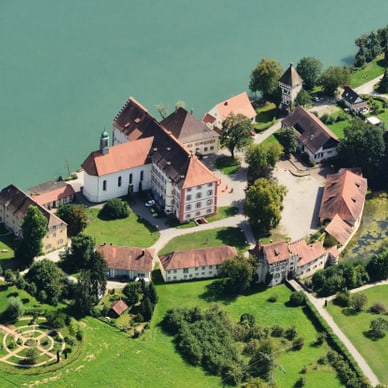 Luftaufnahme eines Schlosses am Fluss mit umliegenden Gebäuden und Gärten.