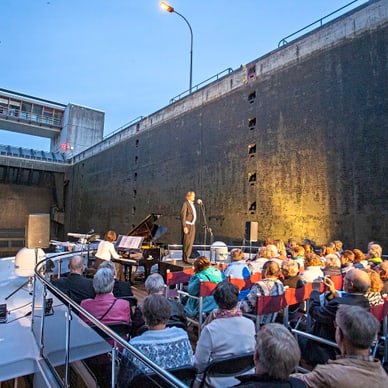 Konzert auf einem Boot in einer Schleusenanlage bei Abenddämmerung.