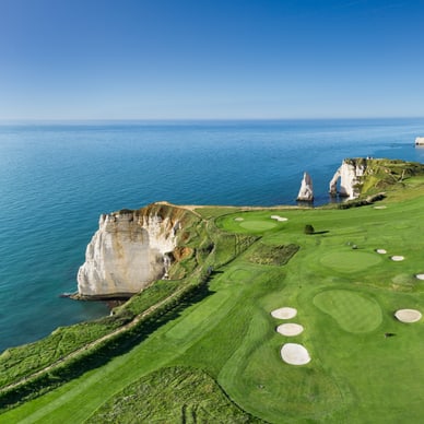 Luftaufnahme des Golfplatzes von Étretat mit grünen Fairways, Sandbunkern und weissen Kreidefelsen an der Küste.