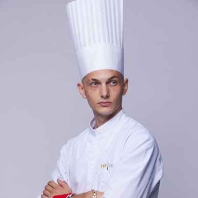 Koch in weisser Uniform und hohem Hut.