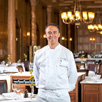 Koch in weisser Uniform in elegantem Restaurant.