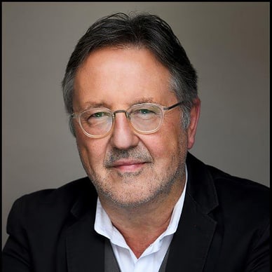 Mann mit Brille in Anzug und Hemd.