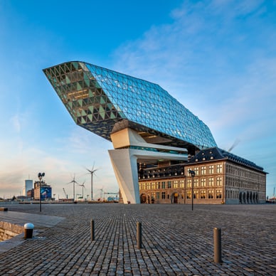 Das Havenhuis in Antwerpen: moderner Glasaufbau von Zaha Hadid über historischer Feuerwache am Hafenbecken.