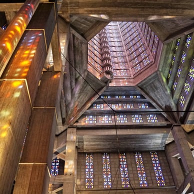 Innenansicht einer Kirche mit bunten Glasfenstern und geometrischem Design.