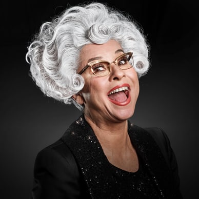 Lachende Person mit weisser Perücke und Brille.