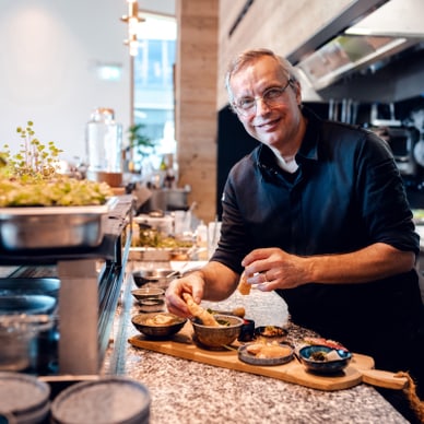 Person im schwarzen Hemd steht in einer Küche und bereitet Essen vor.