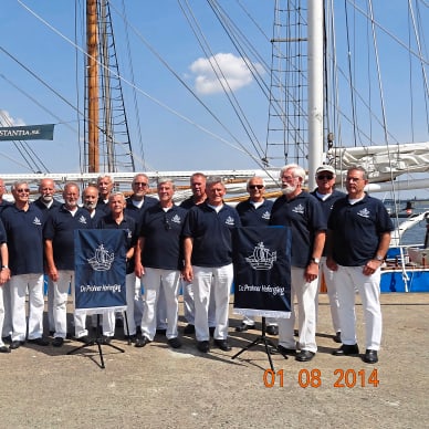 Gruppe von Männern in Uniform vor einem Segelschiff.