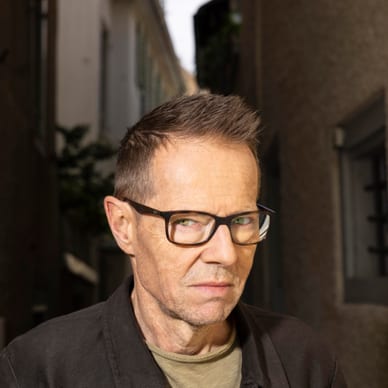 Person mit Brille steht in einem schmalen Durchgang.