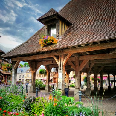 Historischer überdachter Markt mit bunten Blumen im Vordergrund.