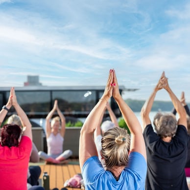 Menschen, die im Freien Yoga machen, mit den Armen über dem Kopf.