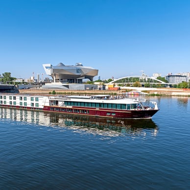 Schiff auf einem Fluss vor einem modernen Gebäude.