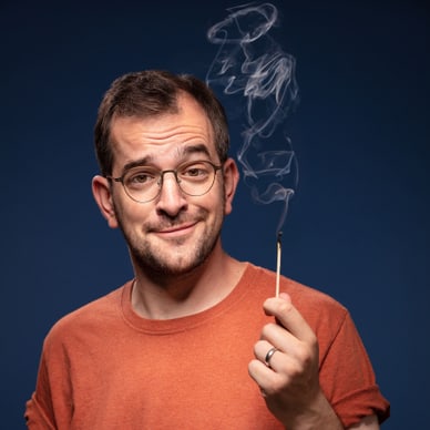 Mann mit Brille hält brennendes Streichholz.