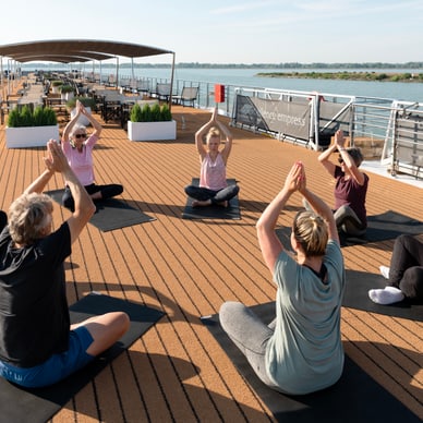 Gruppe macht Yoga auf dem Deck eines Schiffes.