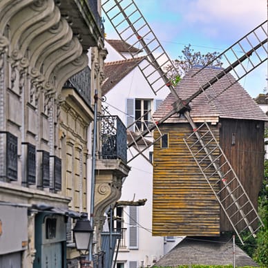 Windmühle zwischen Gebäuden in einer Stadtlandschaft.