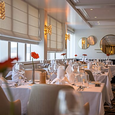 Elegantes Restaurant mit gedeckten Tischen und runden Spiegeln an der Wand.