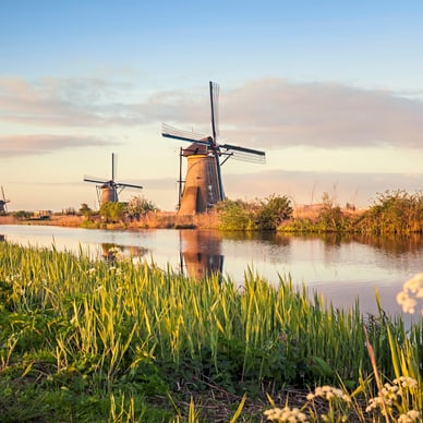 Windmühlen bei Sonnenuntergang am Fluss.