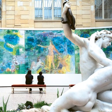 Zwei Personen betrachten ein grosses farbenfrohes Gemälde neben einer weissen Statue im Museum.