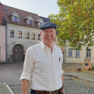 Mann mit Mütze auf einem Platz vor alten Gebäuden.