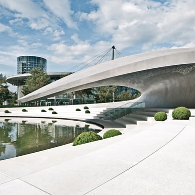 Moderne Architektur mit gewölbtem Gebäude und Teich im Freien.