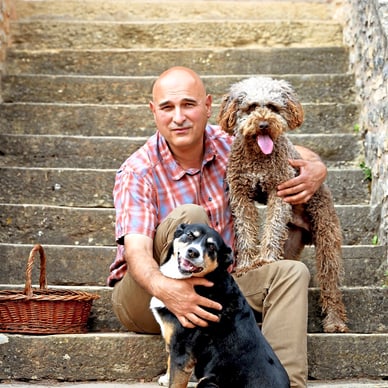 Mann mit zwei Hunden auf einer Steintreppe.