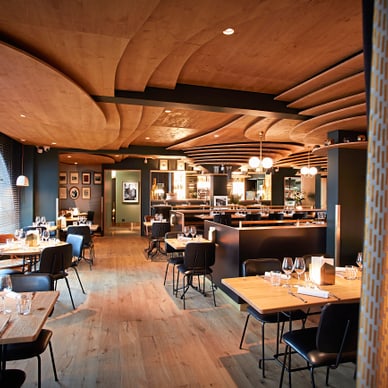 Modernes Restaurant mit Holzdecke und stilvoller Einrichtung.