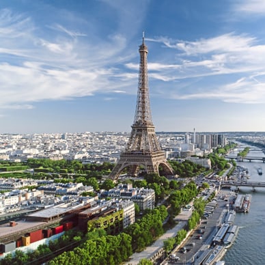 Vogelperspektive auf Paris mit Eiffelturm, Seine und mehreren Brücken unter blauem Himmel.