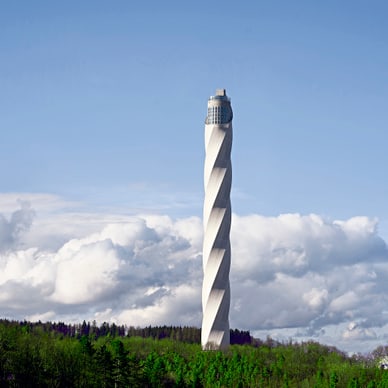 Schraubenförmiger Turm über grüner Landschaft, bewölkter Himmel.
