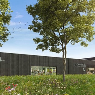 Modernes Gebäude umgeben von Bäumen und Wiese.