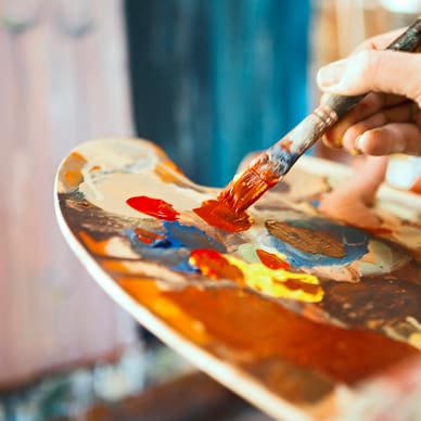 Hand mischt Farben auf einer Malpalette.
