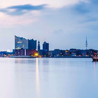 hamburg.jpg Stadtsilhouette bei Dämmerung mit Wasser im Vordergrund.